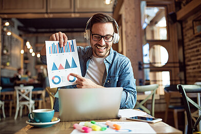 Become a Speaker Mann sitzt vor Laptop und hält Blatt mir Grafiken hoch